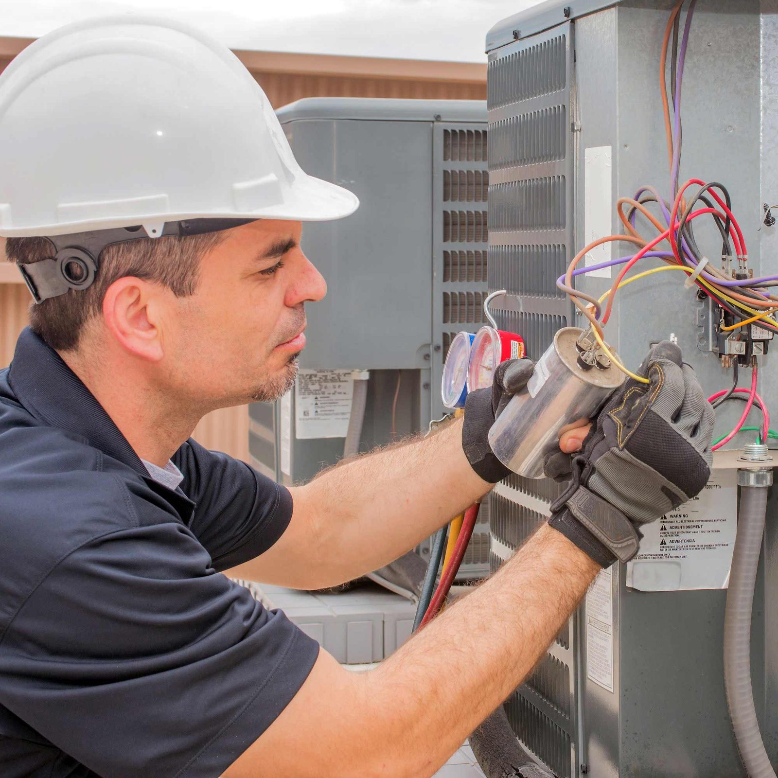 Technician testing the electrical panel of an outdoor AC unit